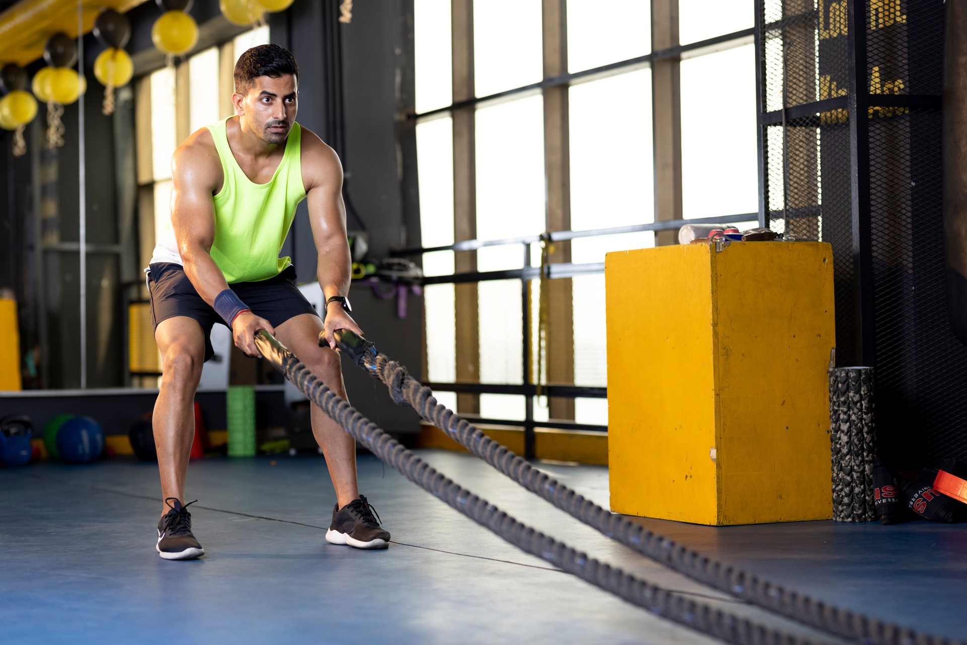 Man training with battle rope in gym gym