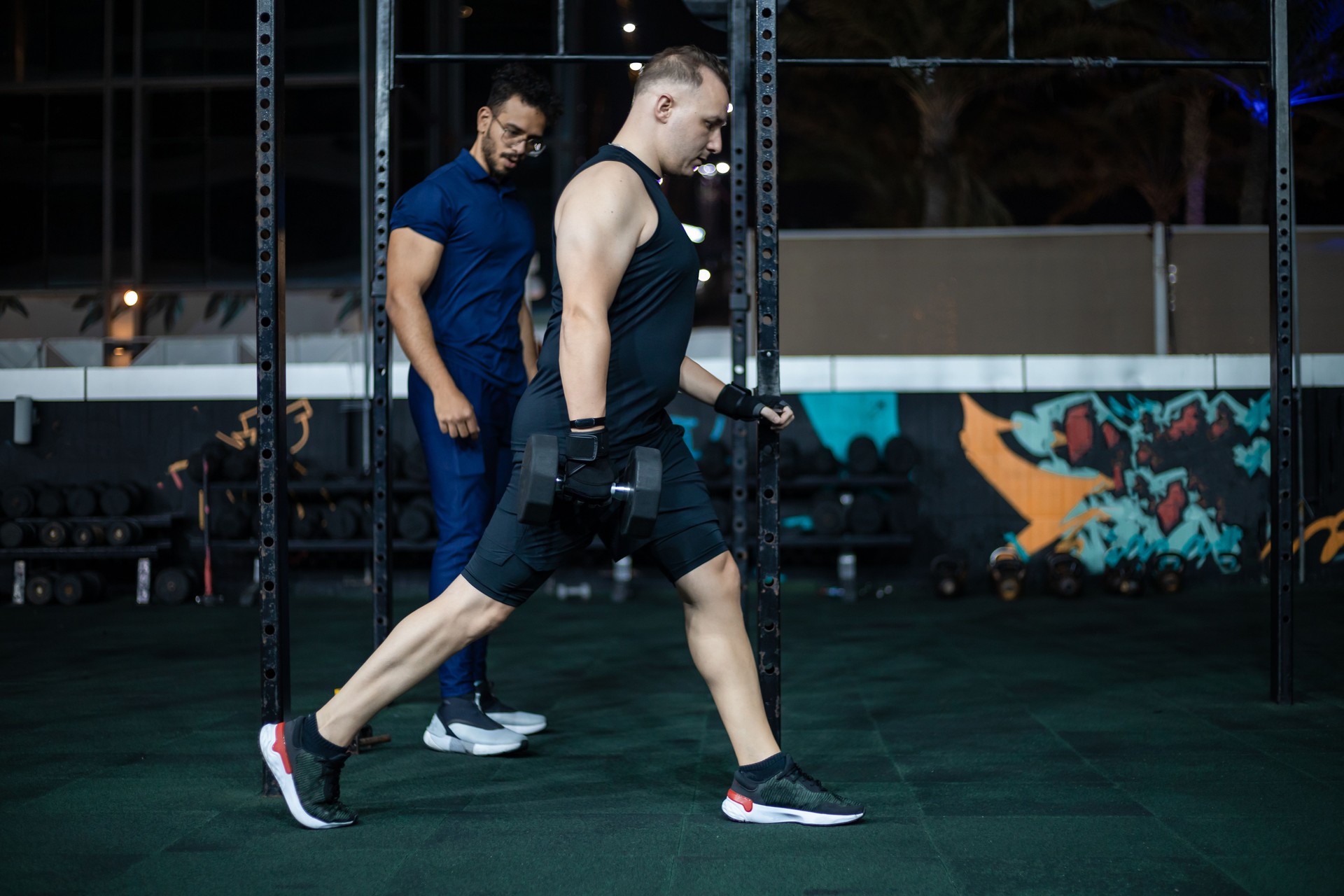 Man Lifting Weights During Personal Training Session In Gym