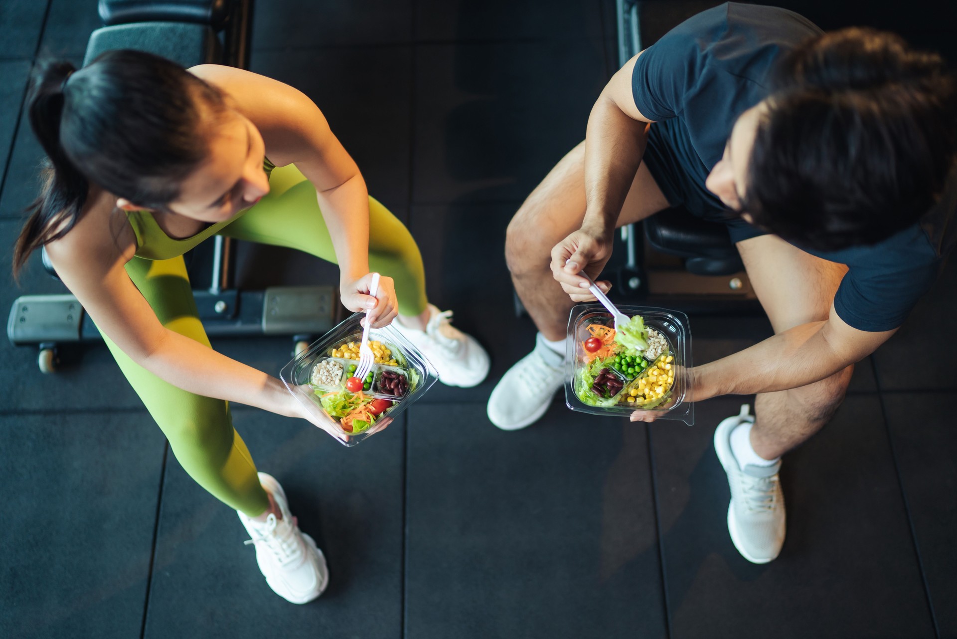 Top view Asian man and woman healthy eating salad after exercise at fitness gym.