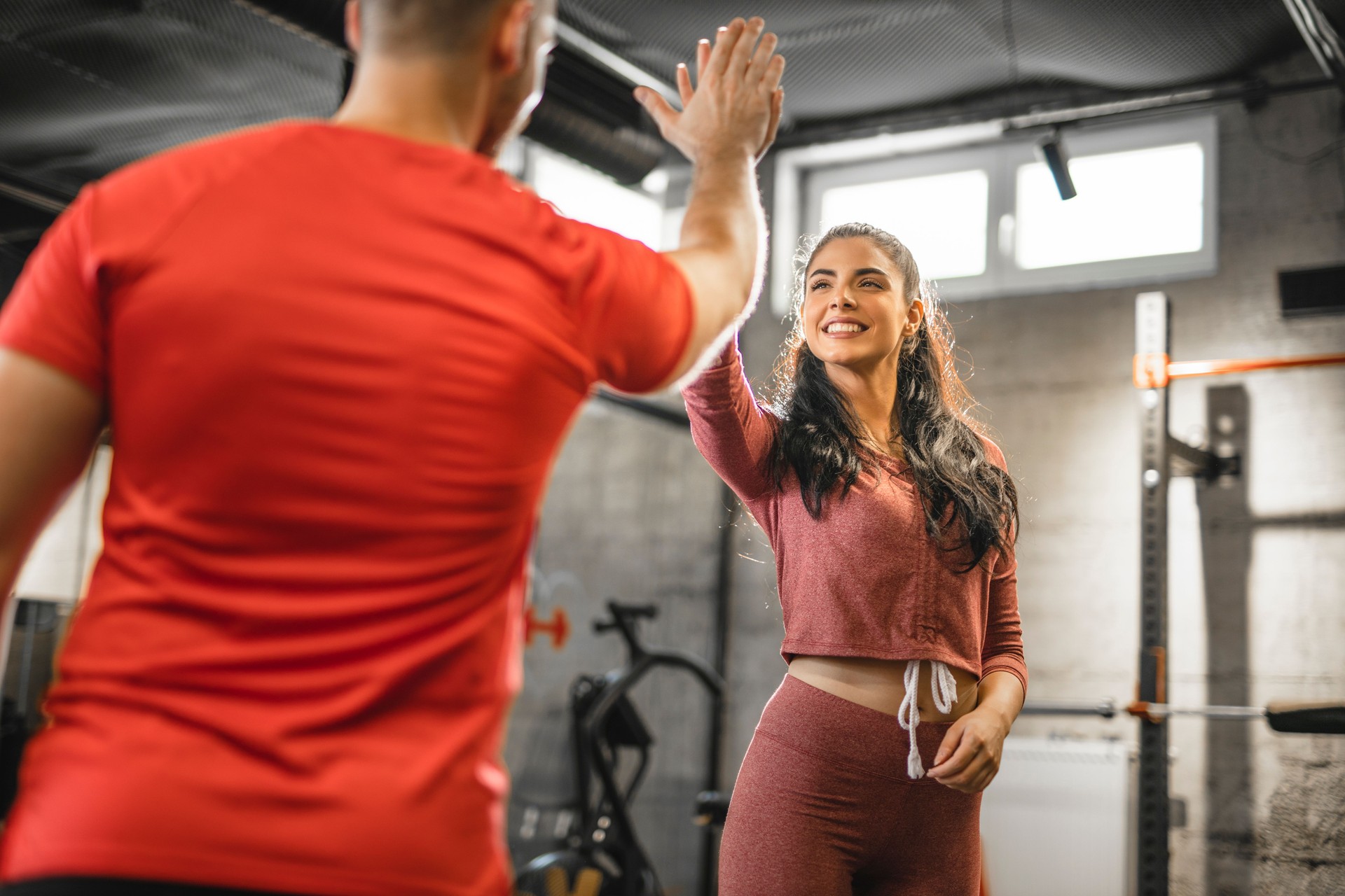 Fitness man and woman giving each other a high five after the training session in gym