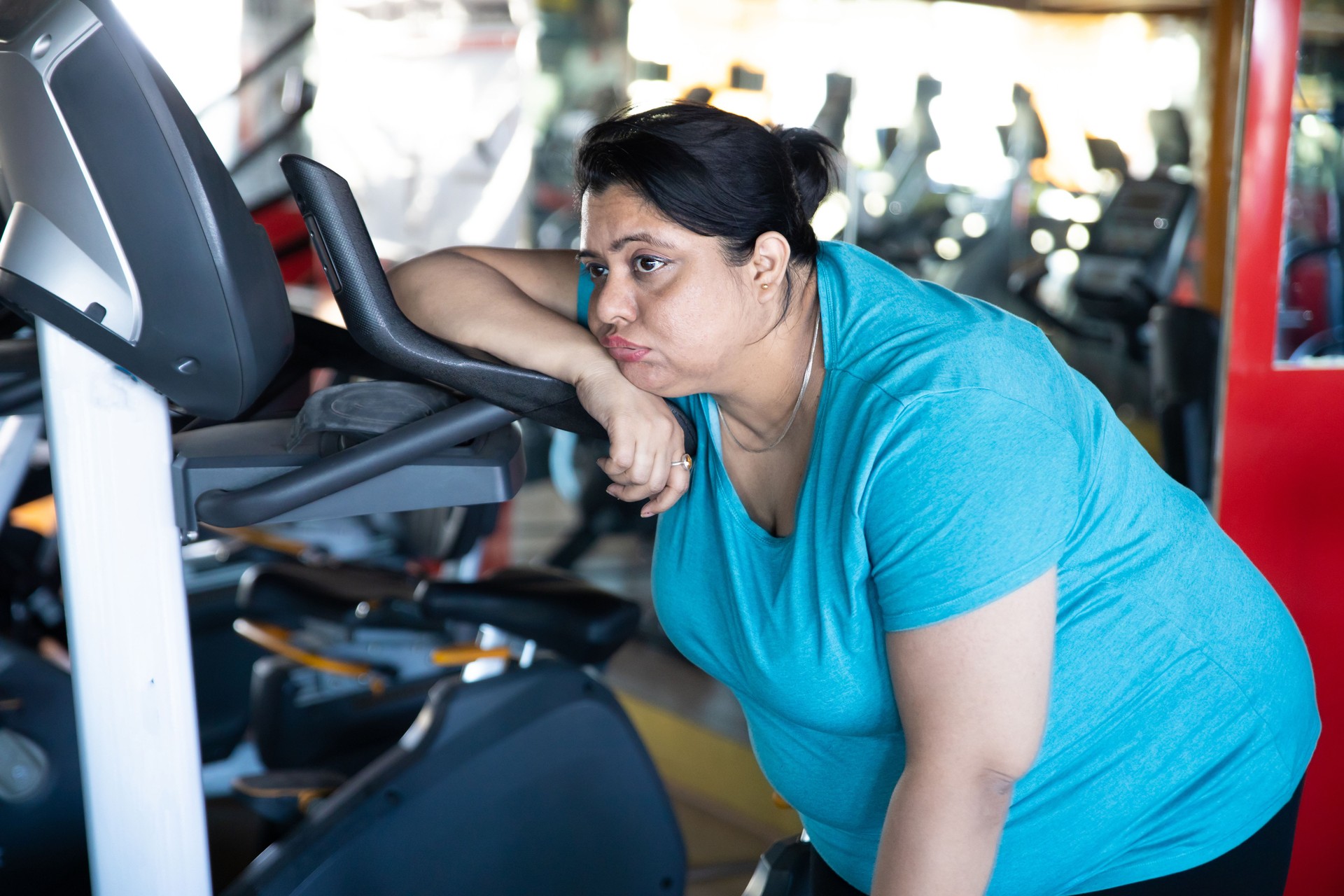 Tired overweight woman sitting on treadmill